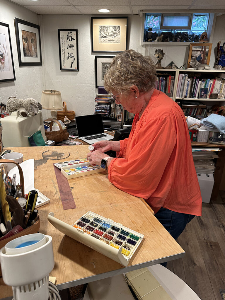 Dr. Susie Myers at working at her drafting table in her studio